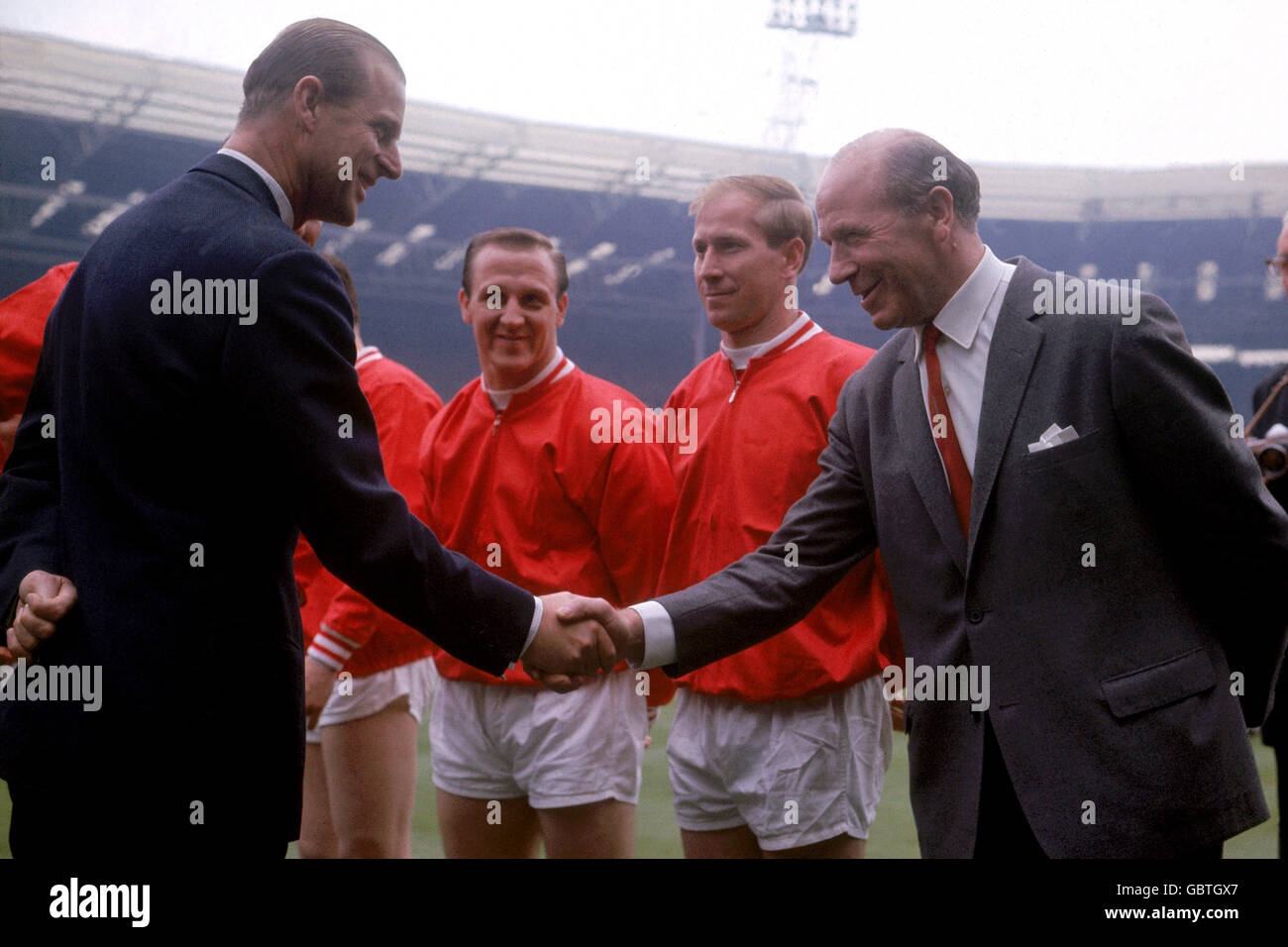 S.H. der Herzog von Edinburgh (l) schüttelt die Hände mit Manchester United-Manager Matt Busby (r) vor dem Spiel als United Maurice Setters (zweite l) und Bobby Charlton (zweite r) Schau mal Stockfoto