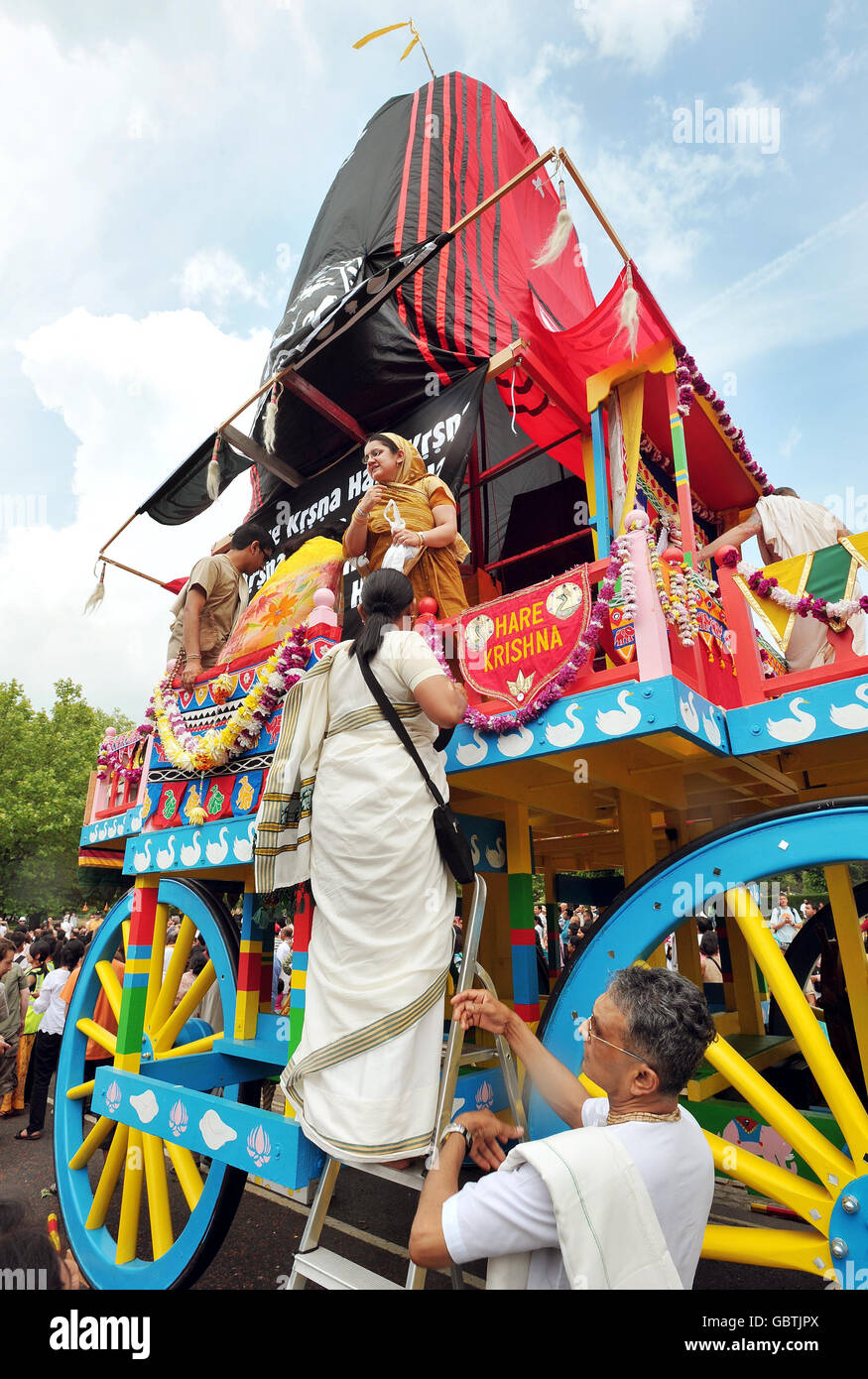 Ein Hare Krishna steigt an Bord eines riesigen dekorativen Schreines mit Rädern, bevor er von Hand vom Hyde Park zum Trafalgar Square gezogen wird, um das „Ratha-yatra“-Festival zu feiern. Stockfoto