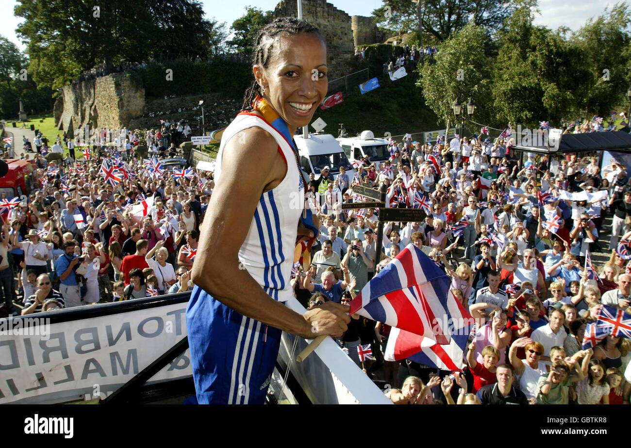 Kelly Holmes zeigt ihre beiden olympischen Goldmedaillen von der Spitze eines offenen Busses, während Tausende von Menschen die Straßen ihrer Heimatstadt Tonbridge in Kent packen, um ihr Zuhause von Athen aus zu begrüßen Stockfoto