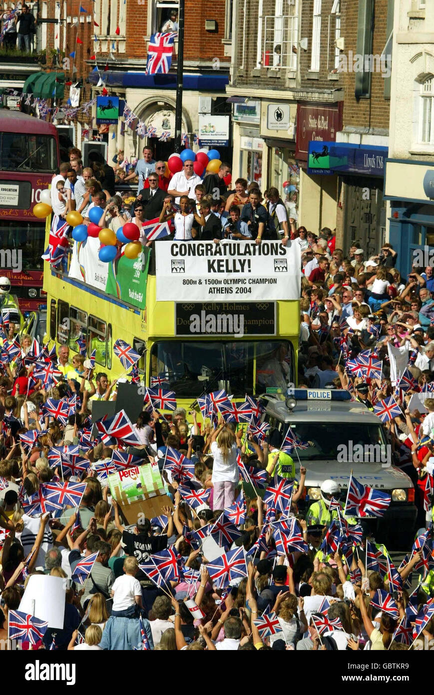 Kelly Holmes zeigt ihre beiden olympischen Goldmedaillen von der Spitze eines offenen Busses, während Tausende von Menschen die Straßen ihrer Heimatstadt Tonbridge in Kent packen, um ihr Zuhause von Athen aus zu begrüßen Stockfoto