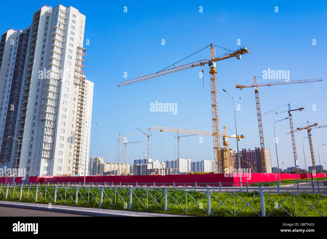 Block von Wohnungen im Bau, Krane arbeiten sind unter blauem Himmel Stockfoto