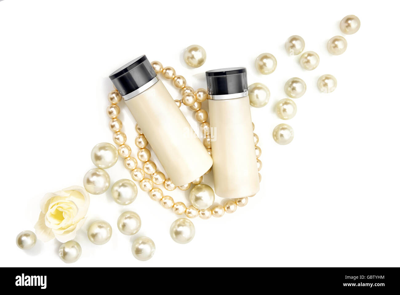 Zwei leere Kosmetikflaschen auf Perlen auf einem Tisch liegend. Studio auf weißem Hintergrund gedreht. Stockfoto