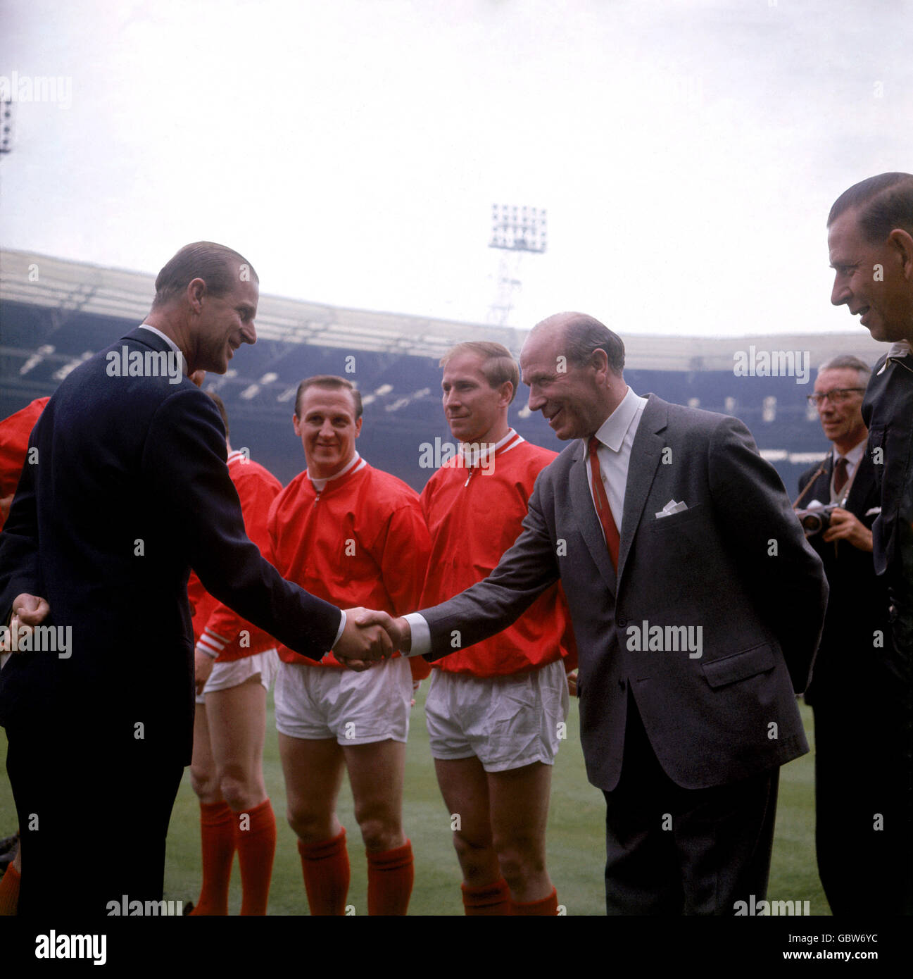 S.H. der Herzog von Edinburgh (l) schüttelt die Hände mit Manchester United-Manager Matt Busby (r) vor dem Spiel als United Maurice Setters (zweite l) und Bobby Charlton (zweite r) Schau mal Stockfoto