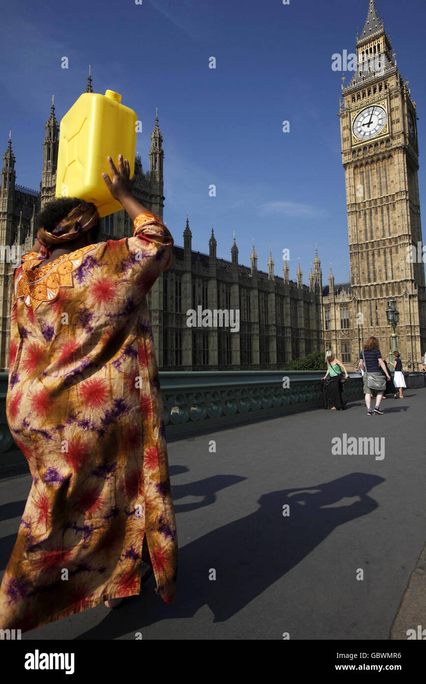 Eine Afrikanerin in traditioneller Kleidung trägt eine mit Wasser gefüllte jerry-Dose von der Themse zur Downing Street in London, wo sie - zusammen mit anderen afrikanischen und asiatischen Frauen - 80,000 Briefe der britischen Öffentlichkeit im Namen der Kampagne „Ende der Wasserarmut“ übergeben wird. Stockfoto