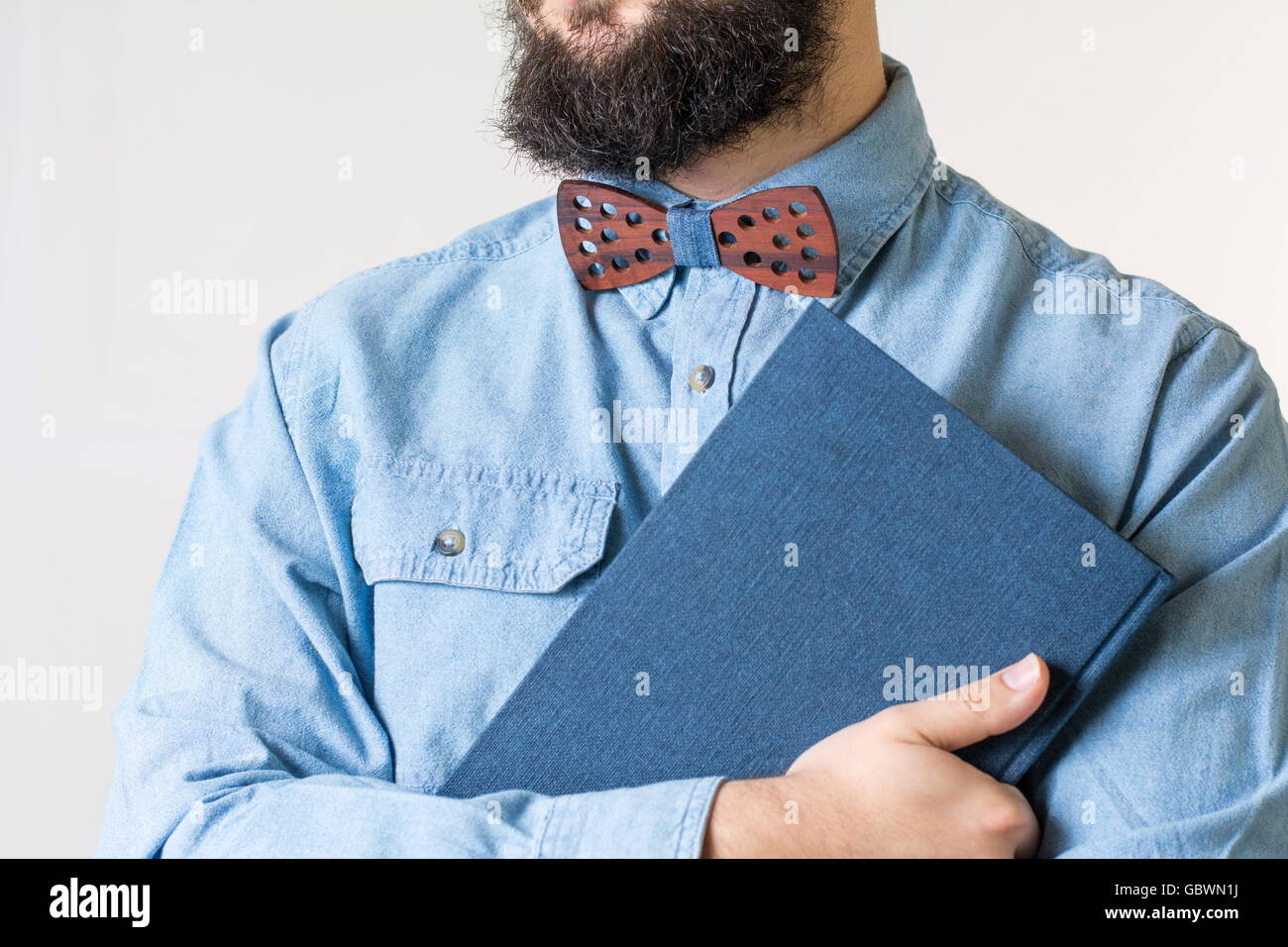 Bärtiger Mann mit einer hölzernen Fliege hält ein blaues Notizbuch Stockfoto