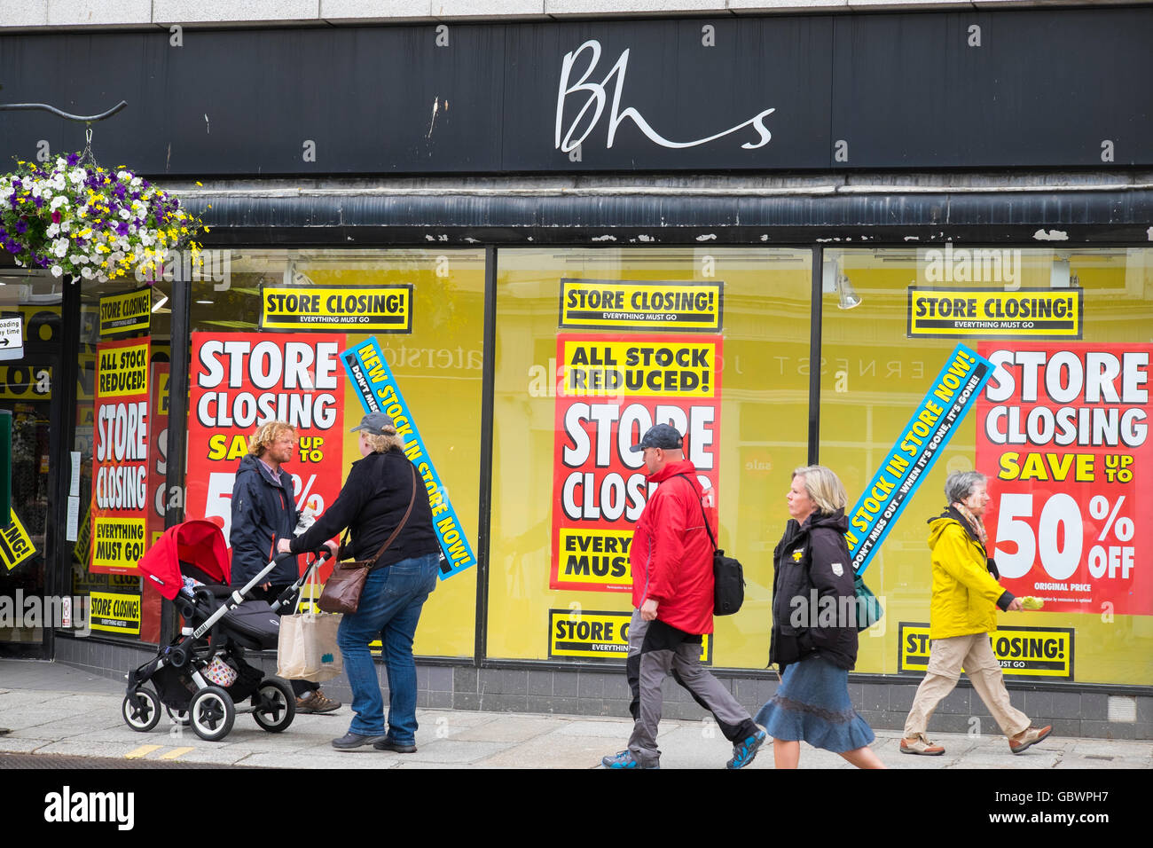 Käufer außerhalb der British Home Stores Shop in Cornwall, England, mit Schließung Verkauf Poster. Stockfoto