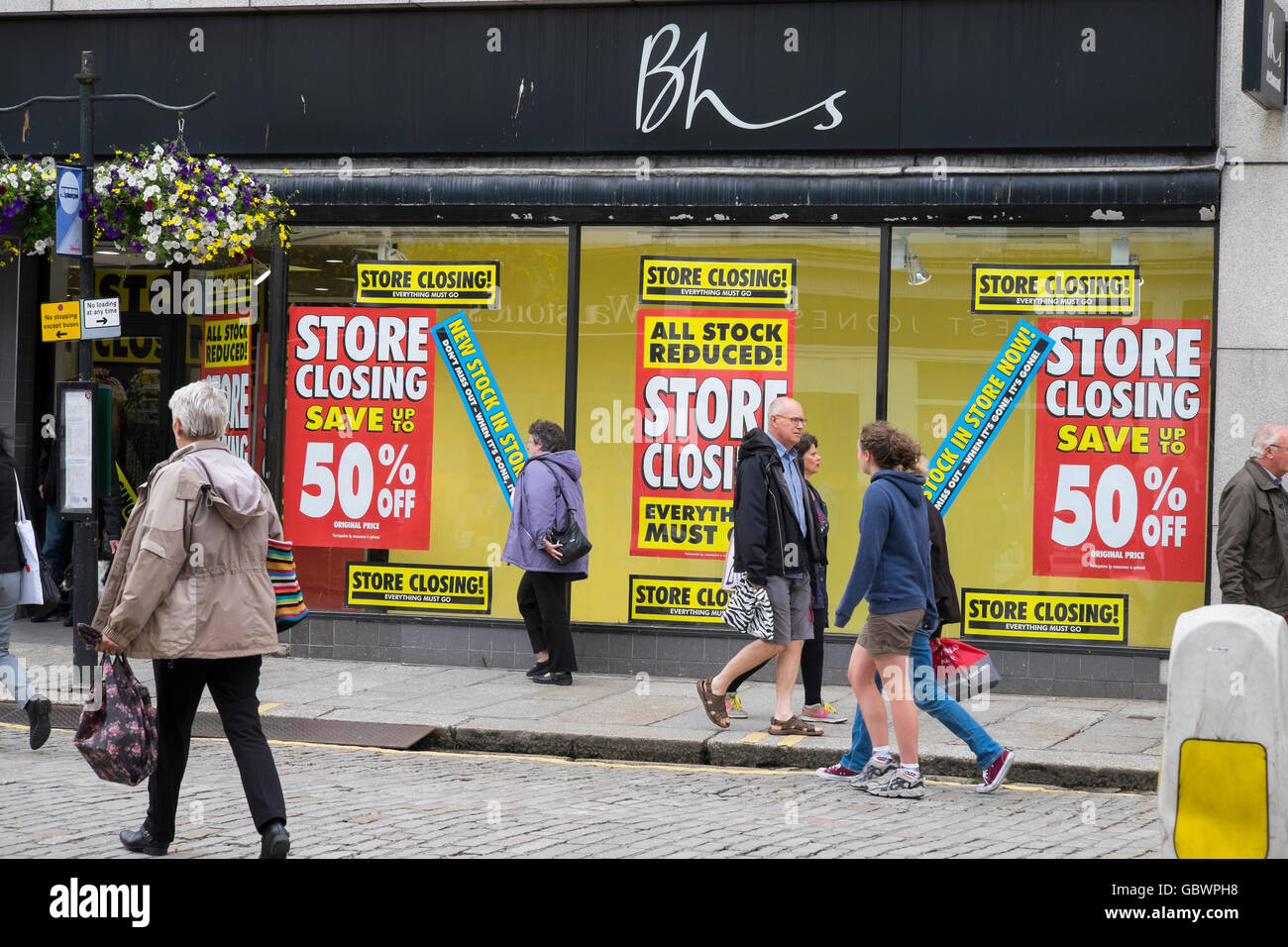 Käufer außerhalb der British Home Stores Shop in Cornwall, England, mit Schließung Verkauf Poster. Stockfoto