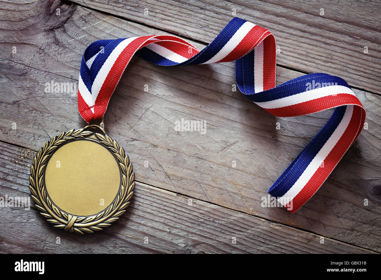 Goldene Medaille auf Holz Hintergrund mit ausdrucksloses Gesicht für Text, Konzept für Erfolg oder Gewinn Stockfoto