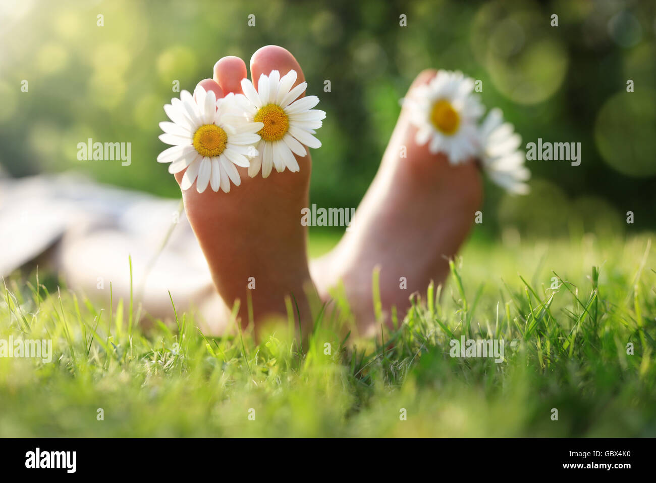 Kind mit Daisy zwischen den Zehen liegen in der Wiese entspannen im Sommersonnenschein Stockfoto