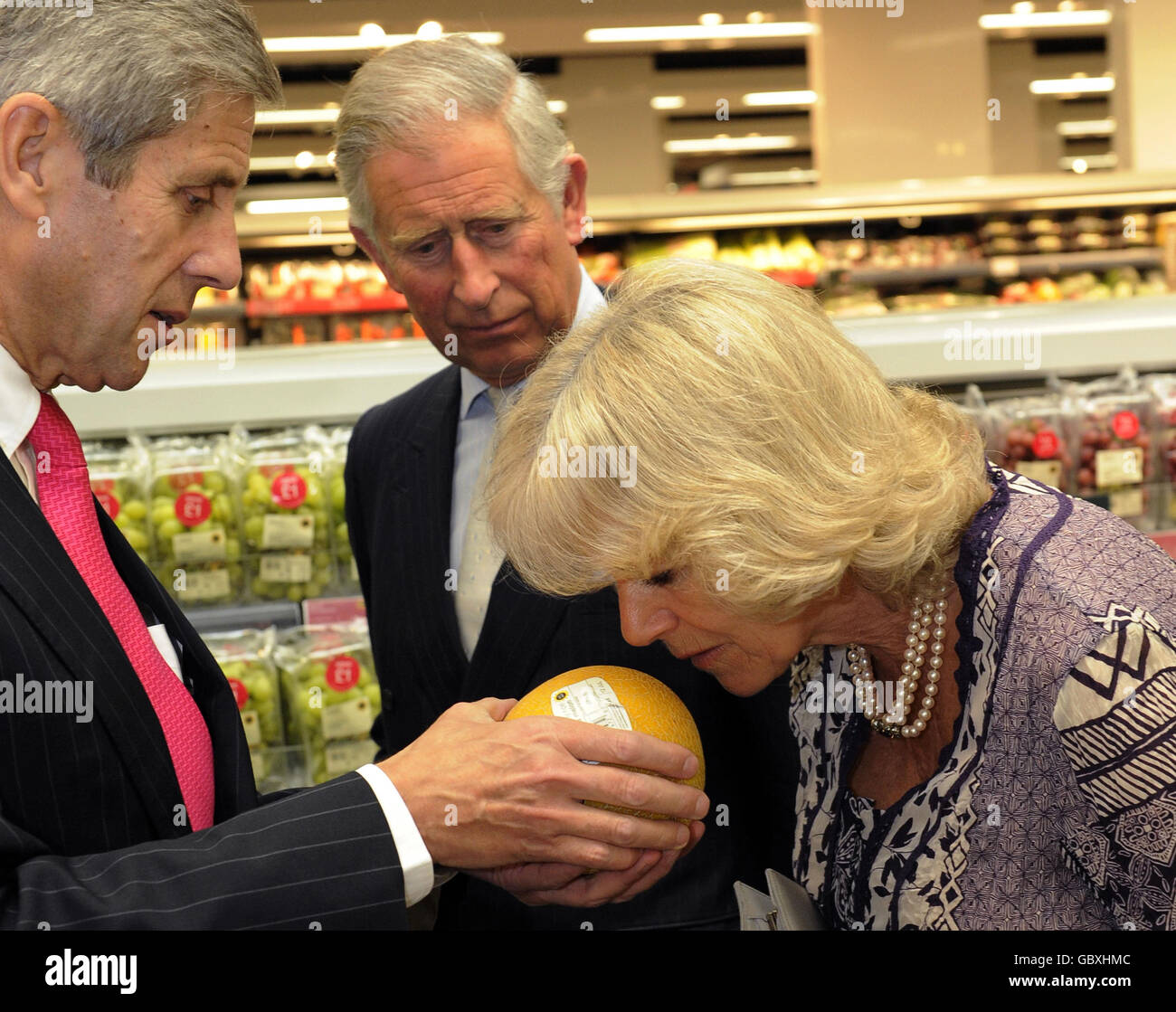 Sir Stuart Rose Executive, Vorstandsvorsitzender von Marks & Spencer, lädt die Herzogin von Cornwall ein, eine Melone zu riechen, während der Prinz von Wales bei einem Besuch in einer Zweigstelle von Marks and Spencer im Westfield Einkaufszentrum in London sieht, um das 125-jährige Jubiläum des beliebten Einzelhändlers zu feiern. Stockfoto