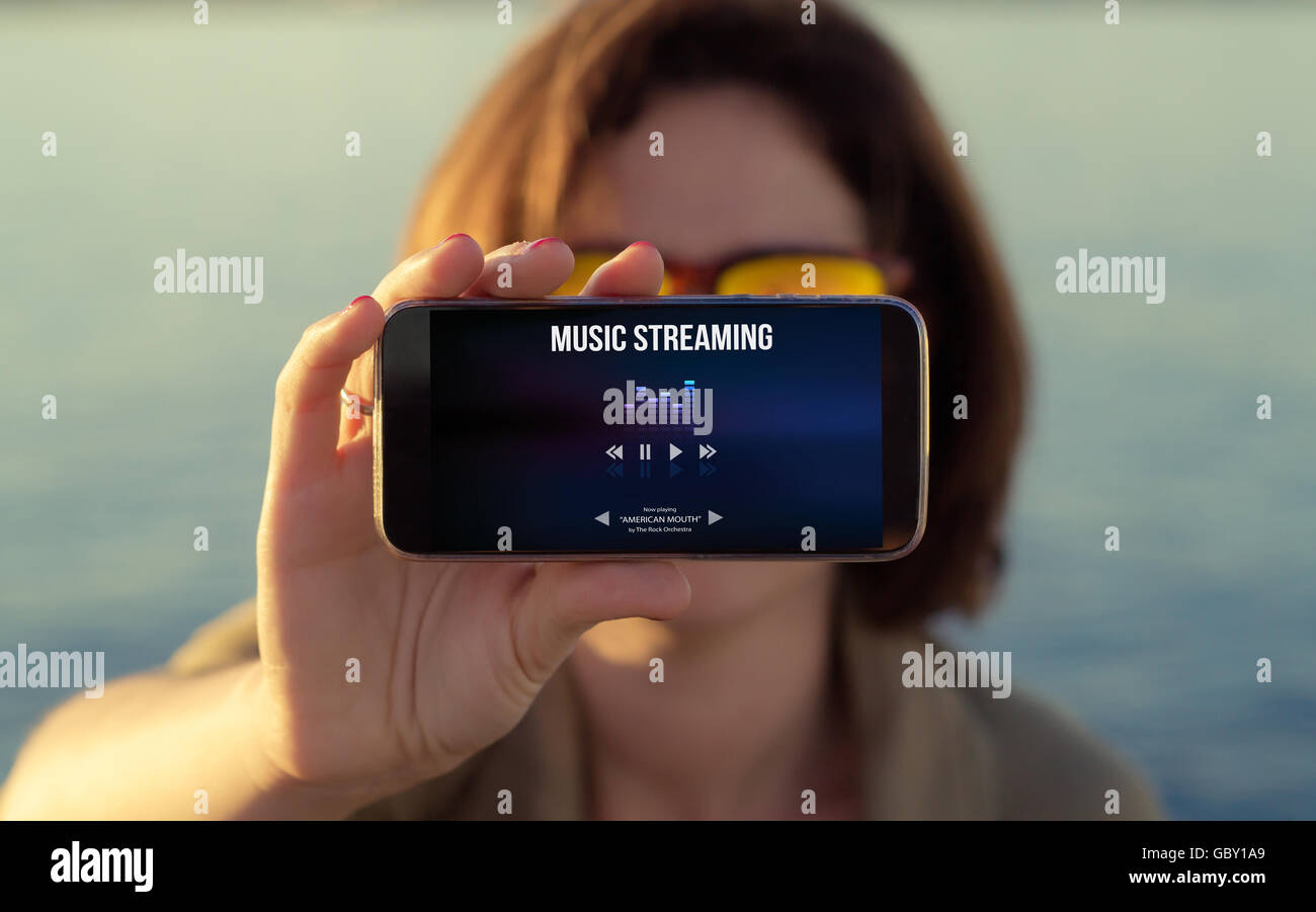 Frau zeigt Musik-streaming auf Handy-Bildschirm. Alle Bildschirm-Grafiken bestehen. Stockfoto