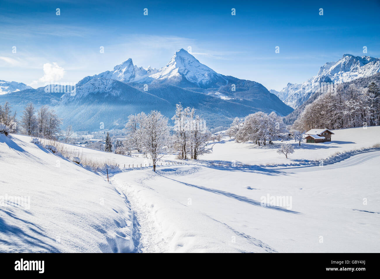 Idyllische Winter Wunderland Landschaft mit Bäumen und Berggipfel in den Alpen an einem sonnigen Tag mit blauem Himmel und Wolken Stockfoto