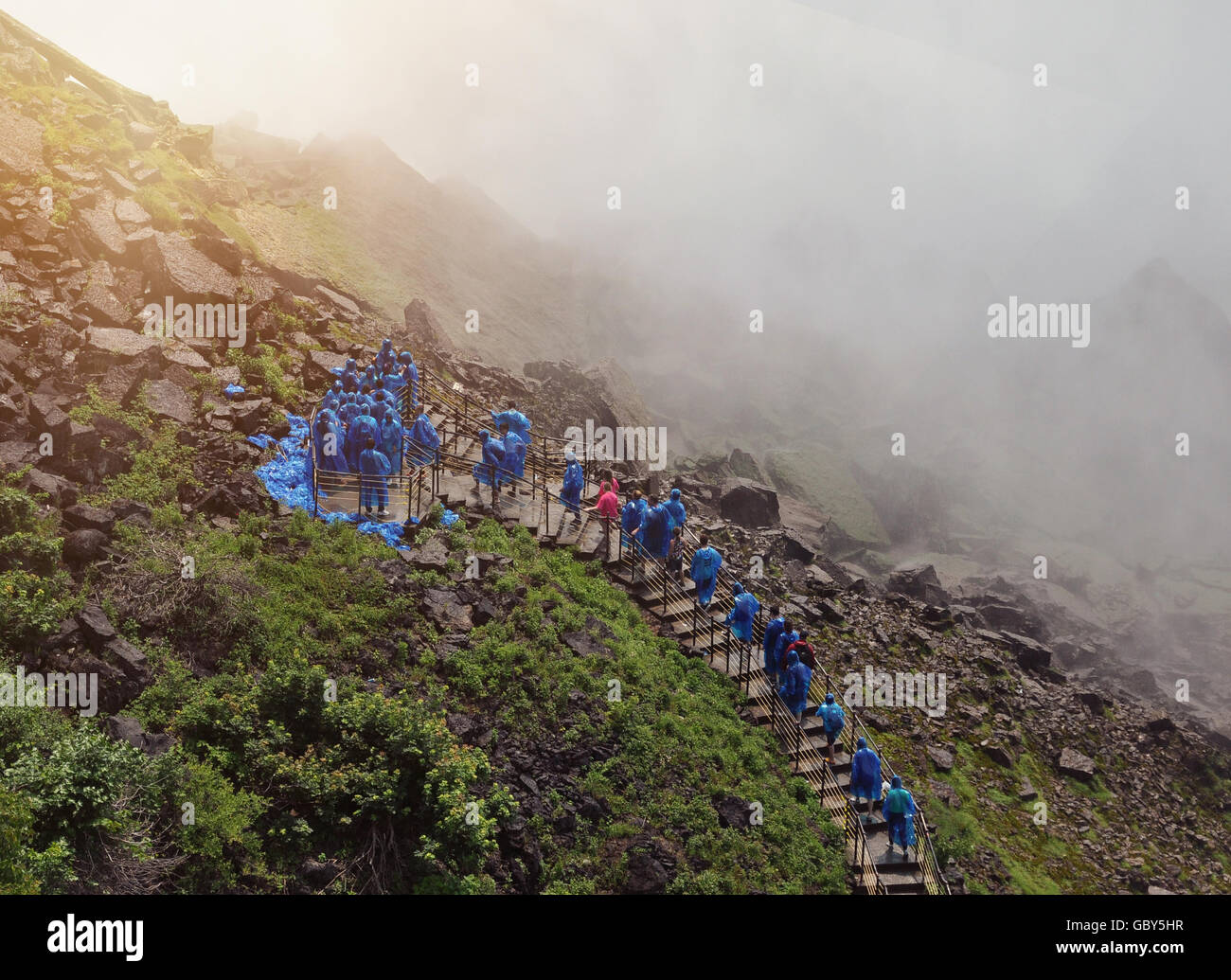 Touristen gehen eine Treppe zu den Niagarafällen mit nassen Wasser Nebel und blau Regenmäntel für eine Reise oder Natur-Konzept auf. Stockfoto