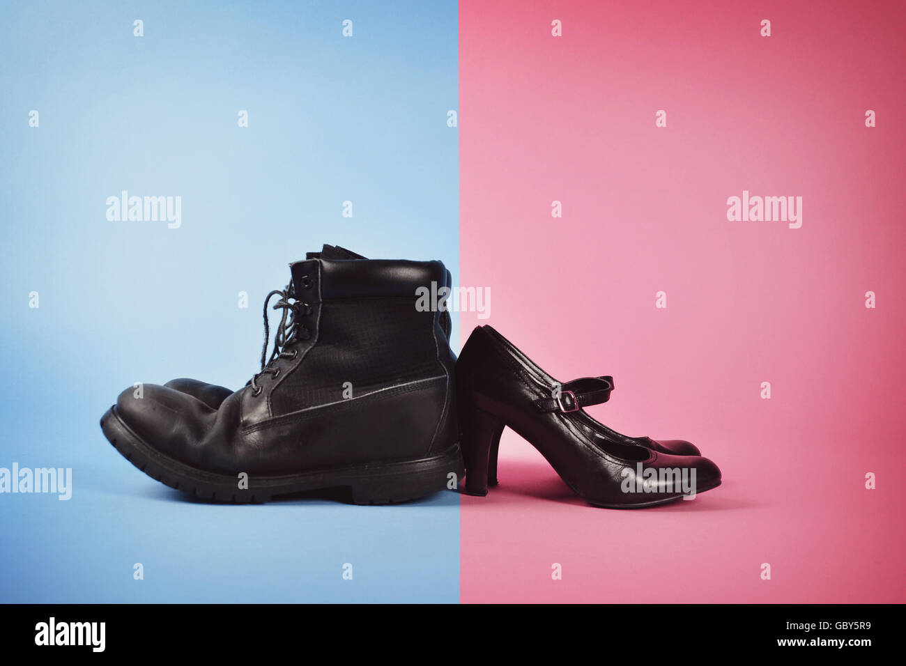 Stiefel des Mannes und der Frau high Heels sind im Hintergrund blau und rosa isoliert für einen Kampf oder Geschlecht Power-Konzept. Stockfoto