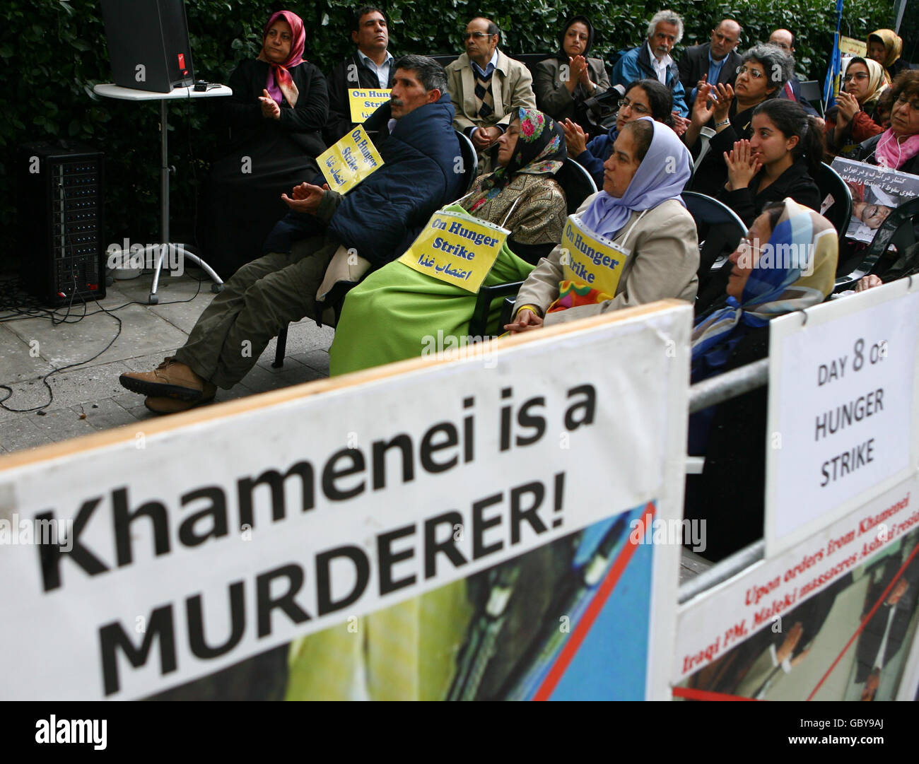 Die Hungerstreikenden Khalil Abadi (2. Links), Jahamshah Jahamshari (3. Links), Fatemeh Khedry (Mitte) und Farzameh Dadkhah (Mitte-rechts), Iraner, die in Großbritannien leben, sehen sich eine Fernsehsendung an, während sie ihren achten Hungerstreik vor der US-Botschaft im Zentrum von London fortsetzen. Stockfoto