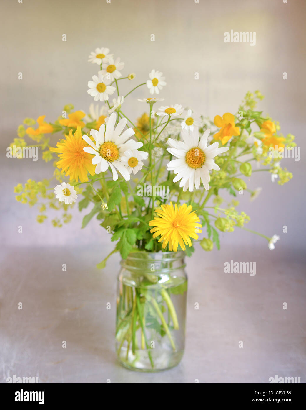 Jam Jar Blumen - ziemlich informellen Anordnung von gelben und weißen Wildblumen in Marmeladenglas Stockfoto