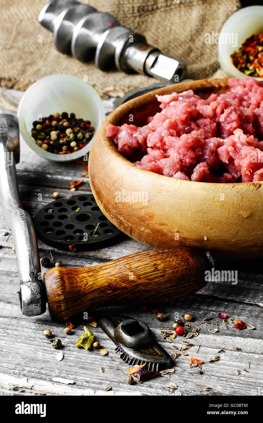 Hackfleisch / Faschiertes und Teile der Fleischwolf auf Holztisch im rustikalen Stil Stockfoto