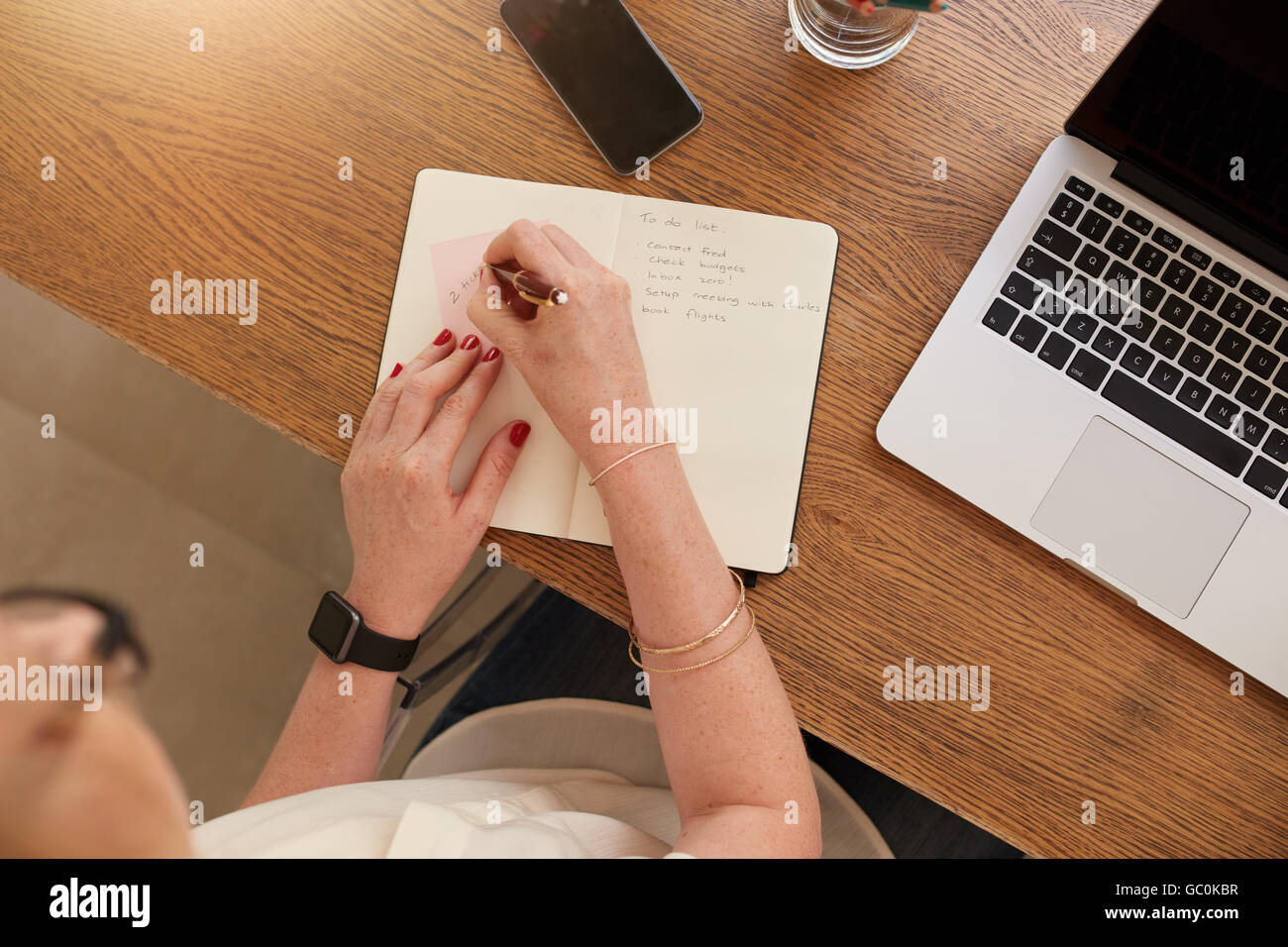 Ansicht von oben-Bild der Frau, die Notizen mit einem Laptop am Tisch. Frau zu Hause arbeiten. Stockfoto