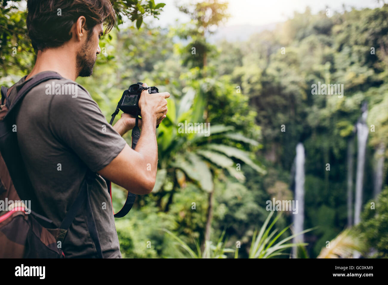 Aufnahme des jungen Mann mit Rucksack ein Foto des Wasserfalls. Männliche Wanderer Fotografieren von einem Wasserfall im Wald. Stockfoto