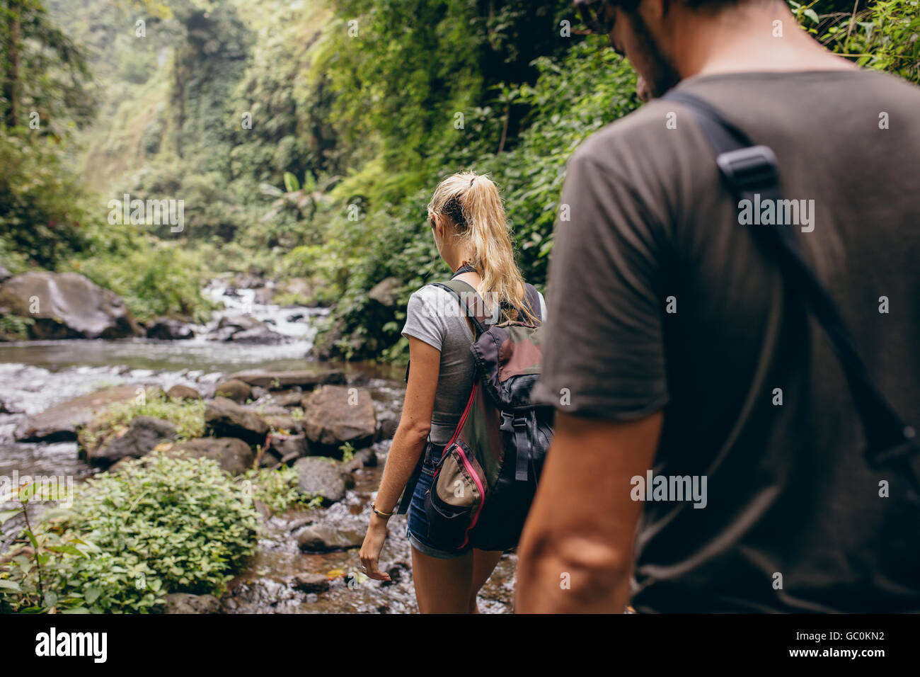 Rückansicht Schuss junger Mann und Frau im Wald wandern. Touristischen Paare, die durch Strom. Stockfoto