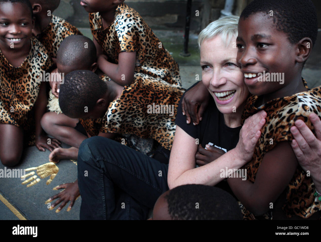 Kinder des African Children's Choir helfen der Sängerin Annie Lennox, vor den Stadtkammern von Edinburgh ein Denkmal für Nelson Mandela zu enthüllen, in dem der Stein die Inschrift der AIDS-Stiftung 46664 von Nelson Mandela trägt. Stockfoto