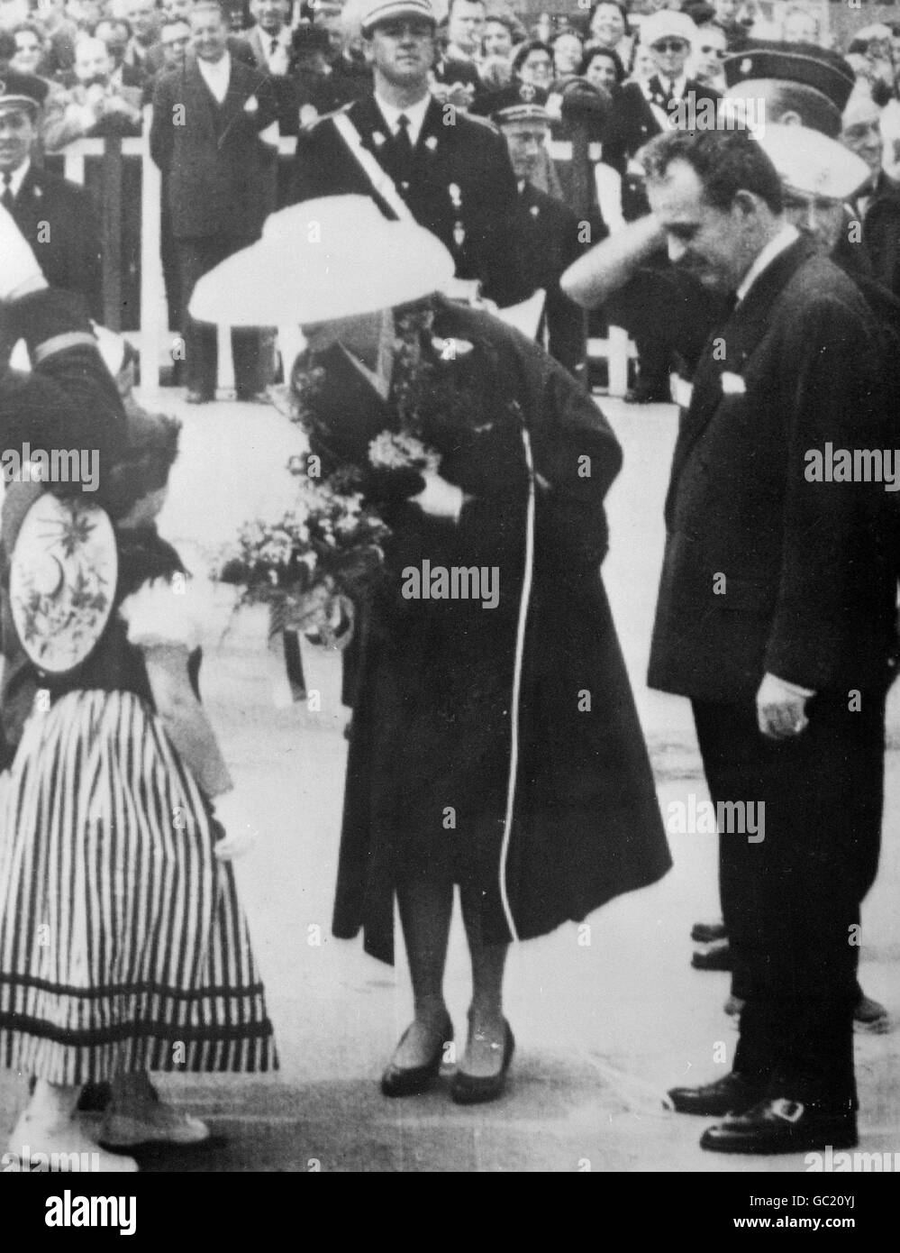 Grace Kelly erhält bei ihrer Ankunft in Monte Carlo aus New York einen Blumenstrauß von einem kleinen Mädchen im monagasischen Kostüm für ihre Hochzeit mit Prinz Rainier von Monaco. Stockfoto