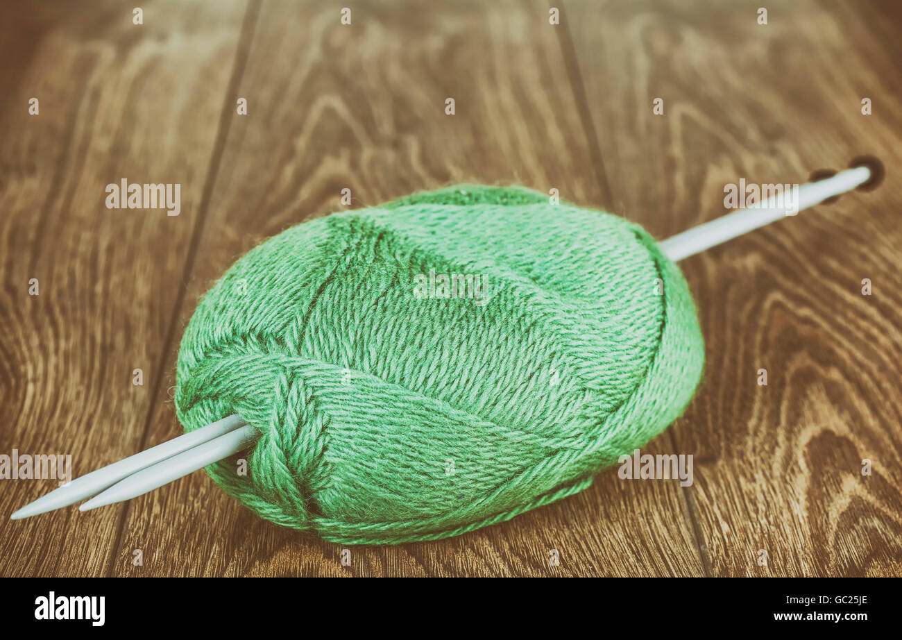 Retro stilisierte Garn mit Stricknadeln auf hölzernen Stock, Hobby oder Ruhestand Konzept. Stockfoto