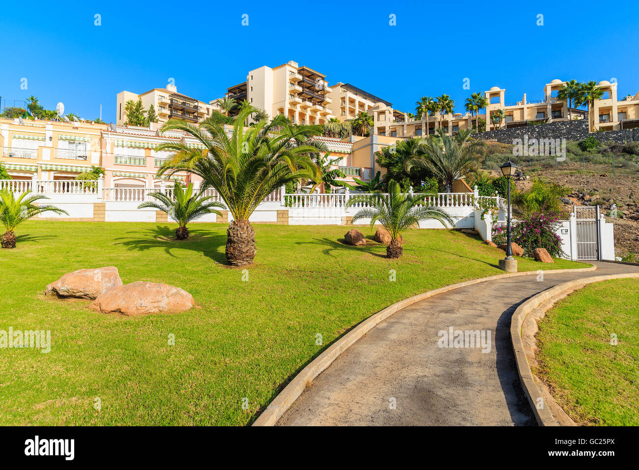 Fuß Gasse in tropischen Park Costa Adeje Stadt mit Ferienwohnungen im Hintergrund, Teneriffa, Kanarische Inseln, Spanien Stockfoto