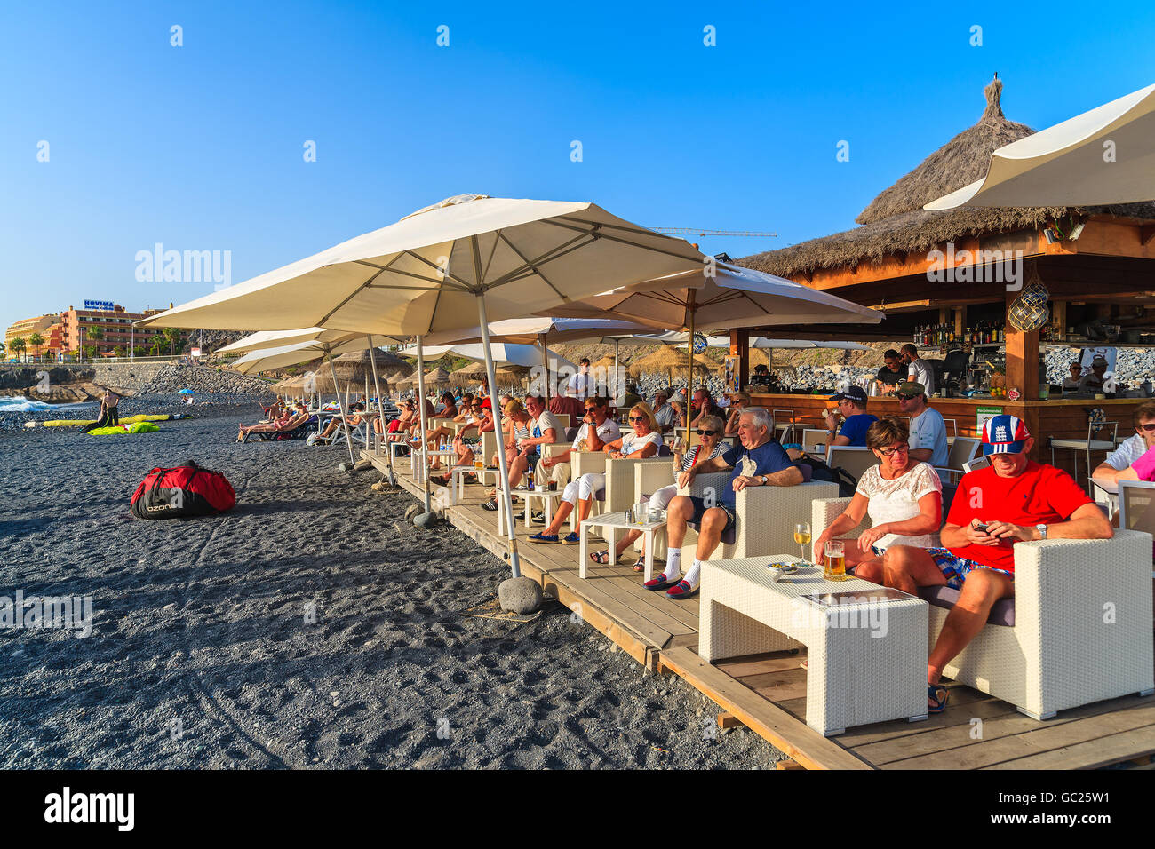 Strand COSTA ADEJE, Teneriffa - 16. November 2015: Touristen sitzen im Strandrestaurant genießen sonniges Wetter und kalte Getränke, Stockfoto