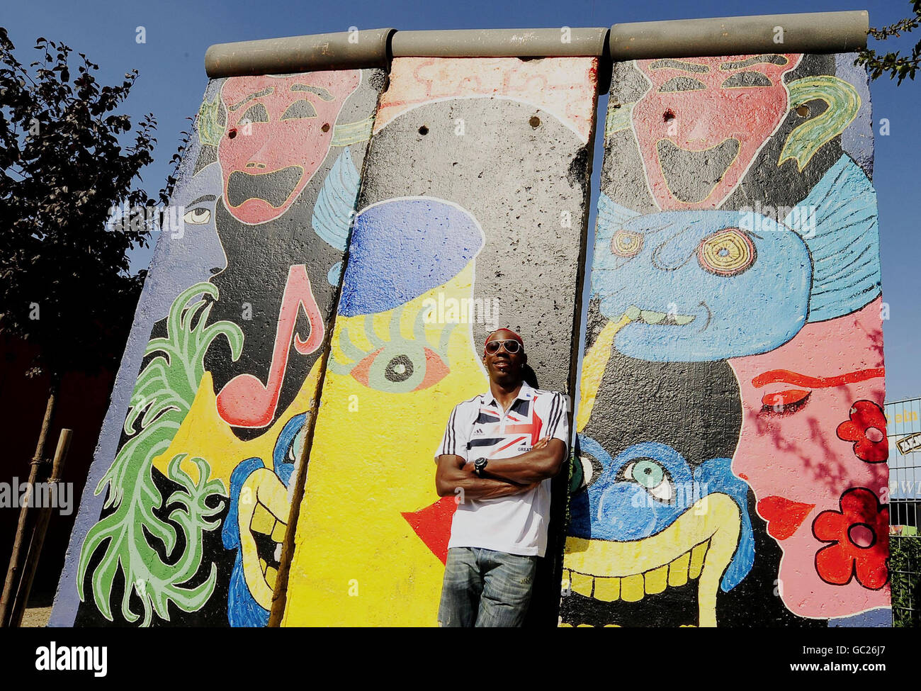 Der britische Phillips Idowu posiert vor der Berliner Mauer für die Medien, nachdem er während der IAAF-Weltmeisterschaft im Olympiastadion in Berlin eine Pressekonferenz auf einem Open-Air-Tourbus hielt. Stockfoto