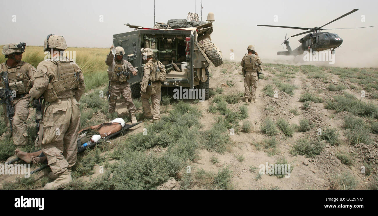 Amerikanische Marineinfanteristen evakuieren einen schwer verletzten afghanischen Polizisten, nachdem sein Fahrzeug aus unbekannten Gründen von einer Brücke aus Khan Neshin in der Provinz Helmand in Afghanistan gefahren wurde. Stockfoto