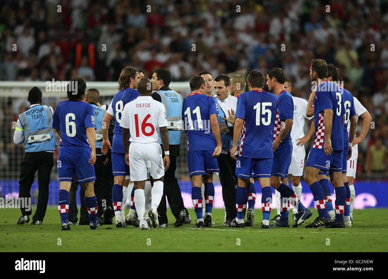 Spieler und Mitarbeiter beider Teams streiten sich auf dem Feld Des Spiels als Stewards versuchen, einen koatianischen Unterstützer zu entfernen Nachdem er rennt weiter, um seine Seite erzielte gegen zu feiern England Stockfoto