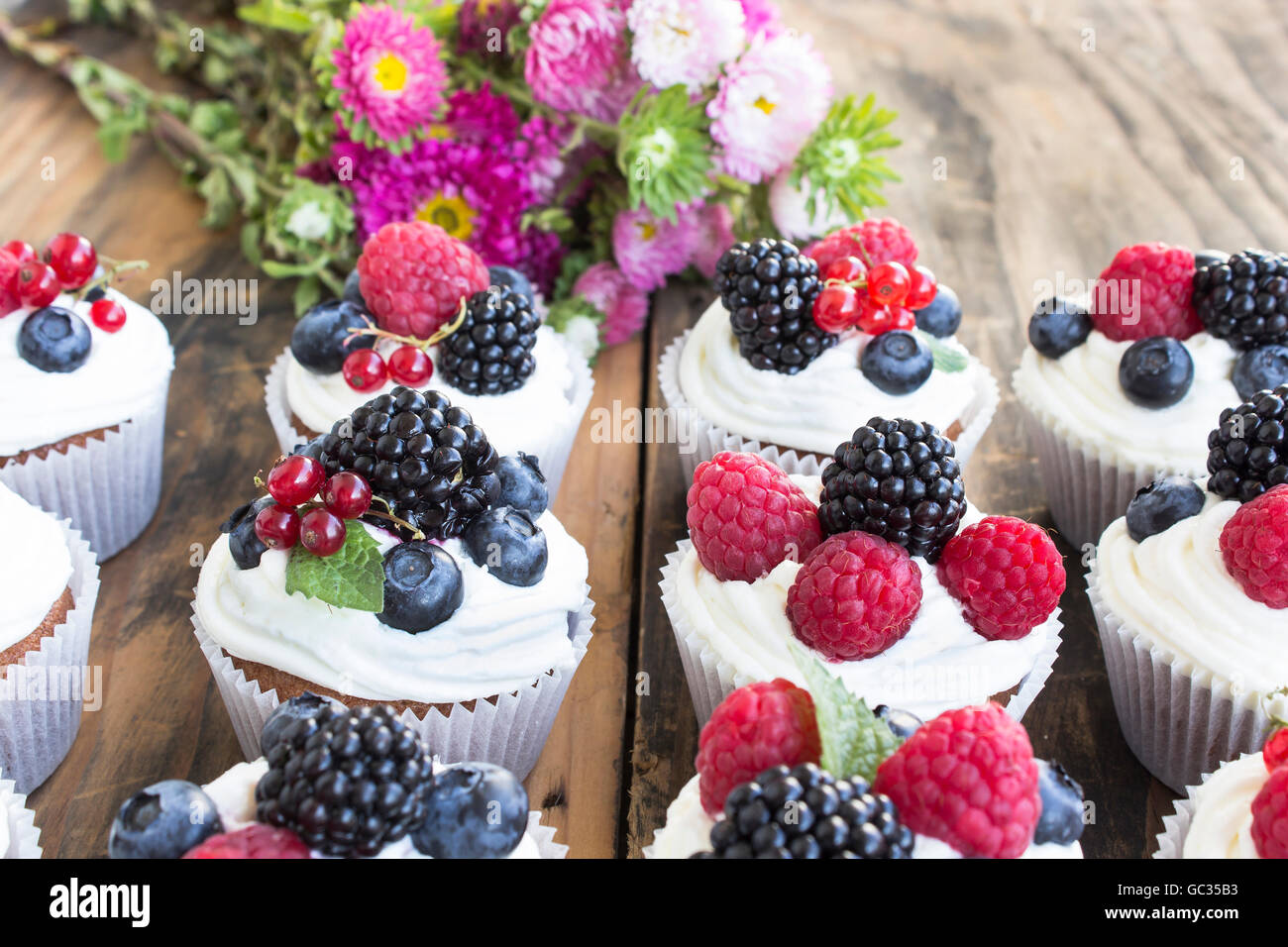 Cupcakes mit Früchten auf einem rustikalen Holztisch. Stockfoto