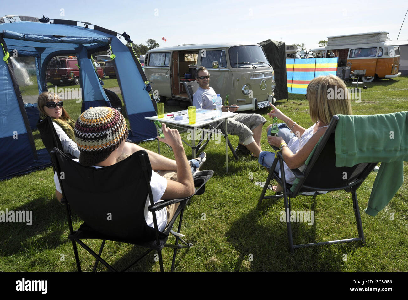 Bei warmem, sonnigem Wetter auf dem Three Counties Showground entspannen sich die Menschen bei einem Bier neben ihren VW-Campingbussen, Malvern, wo es Vanfest Weekend und Tausende von VW-Transporter versammeln sich aus der ganzen Welt in offiziell die größte VW Typ 2 Show der Welt versammeln. Stockfoto
