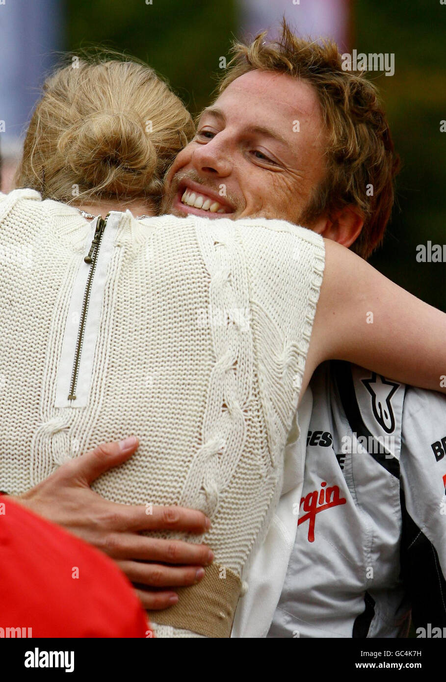 Der Formel-1-Weltmeister Jenson Button wird von Jodie Kidd umarmt, als er während eines Auftritts im Bluewater-Einkaufszentrum in Greenhithe, Kent, die Sieger des Wettbewerbs für eine Fahrt mit einem Sport-Mercedes nimmt. Stockfoto