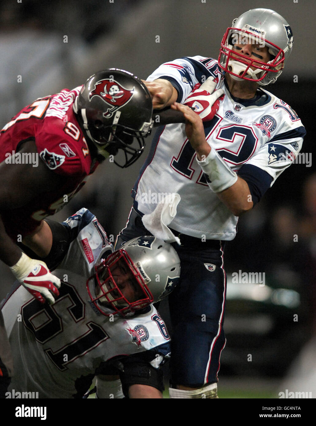 Tom Brady (rechts) von New England Patriots geht vorbei, während Teamkollege Stephen Neal (unten) während des NFL-Spiels im Wembley Stadium, London, ein Tackle von Jimmy Wilkerson von Tampa Bay Buccaneers (links) blockiert. Stockfoto