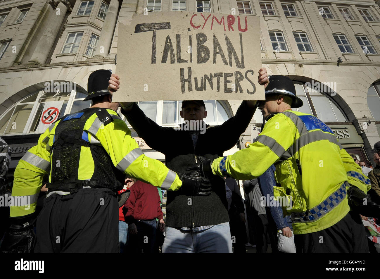 Ein Protestler der Walisischen Verteidigungsliga hält ein selbstgemachtes Plakat mit der Aufschrift „Cymru Taliban Hunters“, da die Their-Gruppe während eines Protestes in der Nähe des Castle Square in Swansea, Wales, von den antifaschistischen Demonstranten von der Polizei getrennt wird. Stockfoto