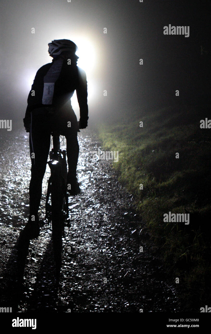 Mountainbiker machen sich auf eine Fahrt in der Nacht mit nur einer Taschenlampe auf, um sich über Felsen und Wälder auf einem der beliebtesten Mountainbike-Strecken Schottlands, Glentress, in den Scottish Borders, durch schwere Hügel zu entzünden. Stockfoto