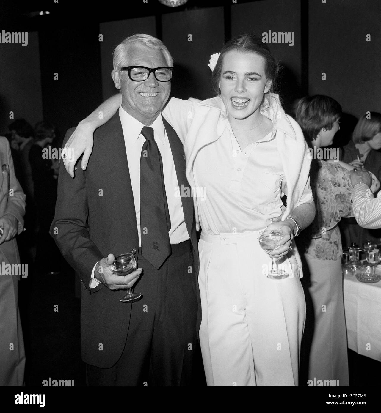 CARY GRANT UND MARGAUX HEMINGWAY BEI EINER COCKTAILPARTY IM LONDONER ROYAL LANCASTER HOTEL, BEI DER EINIGE DER GROSSEN NAMEN DES SHOWBUSINESS DIE MISS HEMINGWAY TREFFEN. Stockfoto