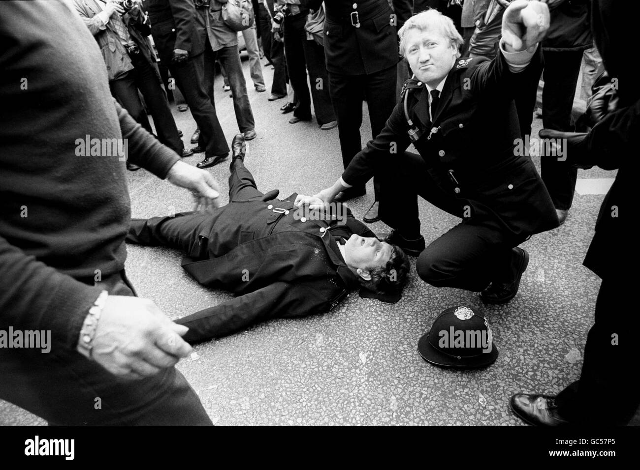 Ein Polizist schreit Befehle, als ein junger Kollege auf dem Boden liegt, der stark aus einer Kopfwunde blutet, nachdem er vor der belagerten Filmverarbeitungsanlage Grunwick im Norden Londons von einer Flasche auf den Kopf getroffen wurde, als Polizei und Streikposten erneut zusammenbrachen. Stockfoto