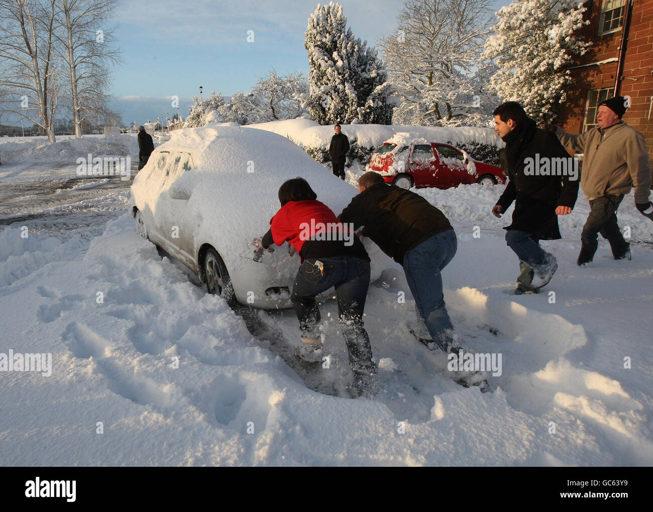 Ein Auto wird geschoben, nachdem er in St. Boswells in den schottischen Grenzen nach einer Nacht mit starkem Schneefall stecken geblieben ist. Stockfoto