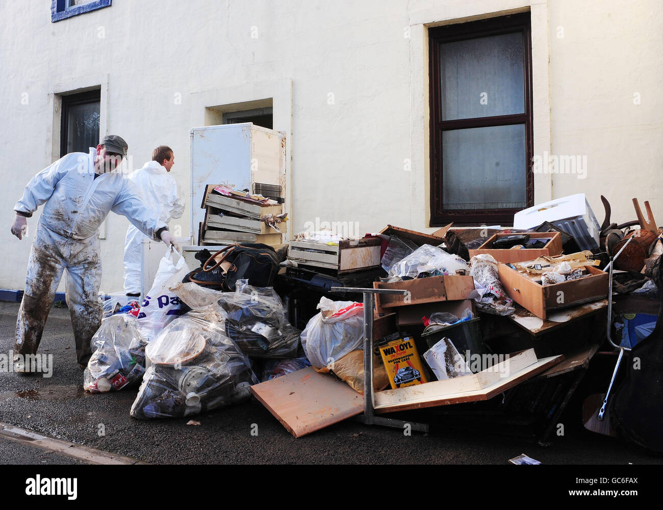 Hausrat und Müllabfuhr überschwemmen überschwemmte Grundstücke in Workington, Cumbria, als die Bewohner ihre Häuser nach den Überschwemmungen in der letzten Woche säubern. Stockfoto