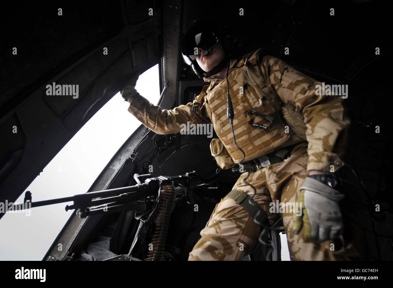 Der führende Aircrewman Mark Spencer wacht über das Haupttor-Maschinengewehr an Bord eines Sea King Hubschraubers, während er über afghanische Siedlungen fliegt, die von Camp Bastion nach Laskar Gah und Forward Operating Base (FOB) Pimon führen, als Teil der täglichen Aufgabe der Joint Helicopter Force, lebenswichtige Truppen und Ausrüstungswagen zu befahren In und um die Provinz Helmand in Afghanistan. Stockfoto