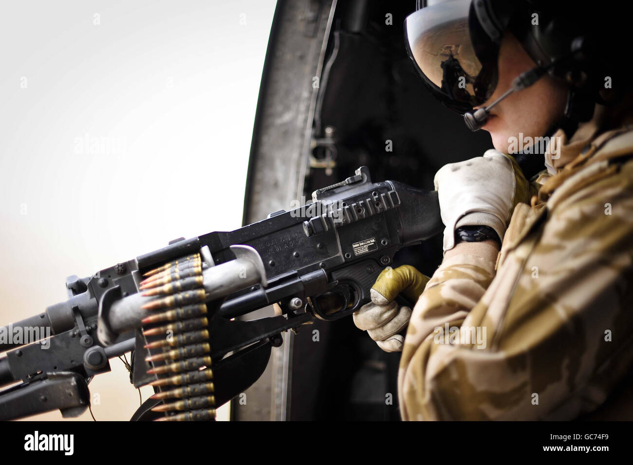 Der führende Aircrewman Mark Spencer wacht über das Haupttor-Maschinengewehr an Bord eines Sea King Hubschraubers, während er über afghanische Siedlungen fliegt, die von Camp Bastion nach Laskar Gah und Forward Operating Base (FOB) Pimon führen, als Teil der täglichen Aufgabe der Joint Helicopter Force, lebenswichtige Truppen und Ausrüstungswagen zu befahren In und um die Provinz Helmand in Afghanistan. Stockfoto