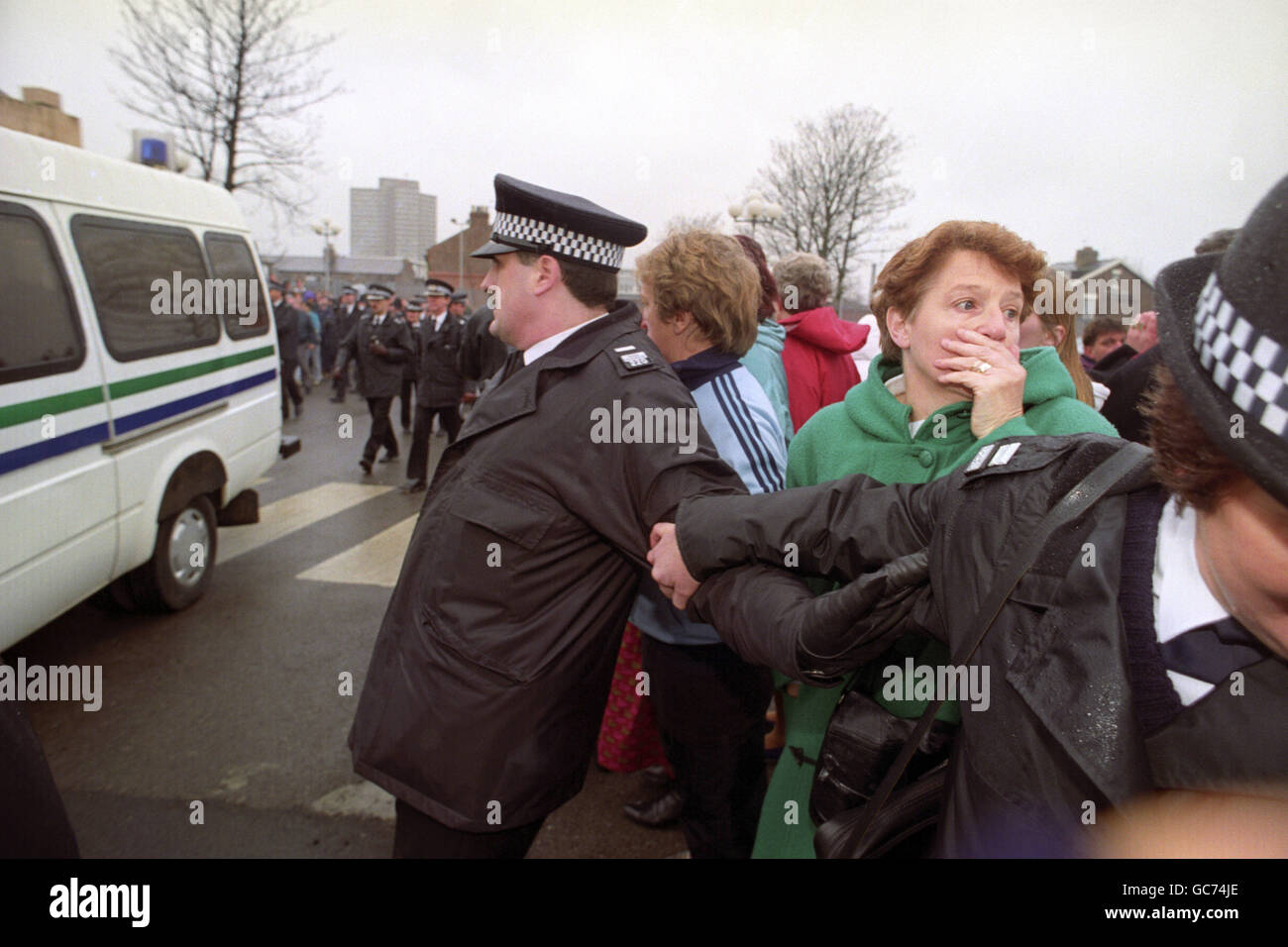 ANGST ZEIGT SICH AUF DEM GESICHT EINER JUNGEN FRAU HINTER POLIZEIBARRIEREN, ALS DER KONVOI, DER DIE ZWEI- BIS ZEHNJÄHRIGEN MITBEWOHNENDEN TRÄGT, DIE WEGEN DES MORDES AN JAMES BULGER ANGEKLAGT SIND, DAS AMTSGERICHT VON SOUTH SEFTON VERLÄSST. 3/4 MENSCHEN SCHNAPPTEN SICH HINTER DER BLAUEN LINIE, ALS DER VAN VORBEIFÄHRT. Stockfoto