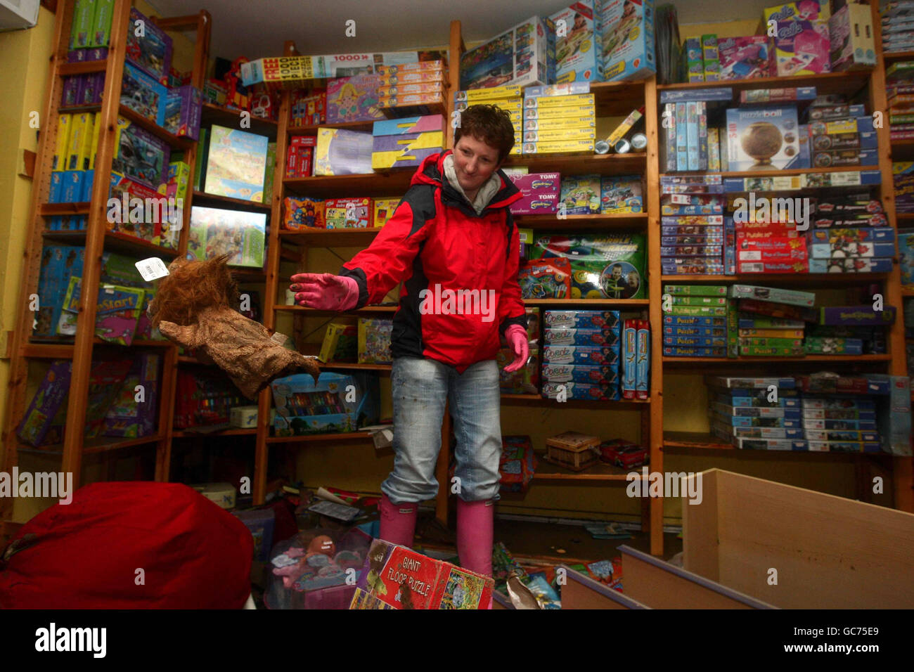 Alison Watson wirft in ihrem Geschäft Al's Toys im Stadtzentrum von Cockermouth nach den jüngsten Überschwemmungen eine zerstörte Handpuppe weg. Stockfoto