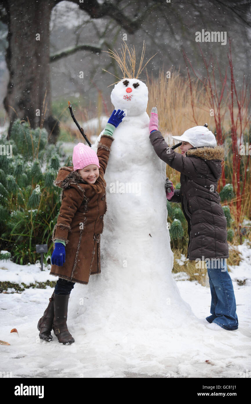 Sarah Aoudia, 7, und Kim Gaynor, 10, mit einem Schneemann, der von Mitarbeitern in den Londoner Kew Gardens hergestellt wurde. Stockfoto