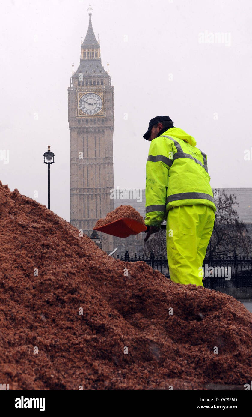 Ein Straßenputzer verteilt Salz und Splitt über die Straßen von Westminster in London heute als starker Schnee fiel in der ganzen Hauptstadt. Stockfoto