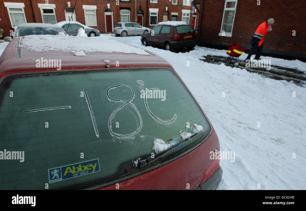 Ein Postbote liefert seine Post, während die Nachttemperatur in Eis auf einem Auto in Stockport geschrieben wird, da die arktischen Bedingungen weiterhin den Norden Englands treffen. Stockfoto