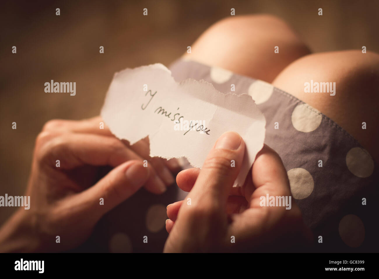 Draufsicht der Frau im gepunkteten Kleid hält eine Papier-Nachricht mit dem Text I miss you Stockfoto